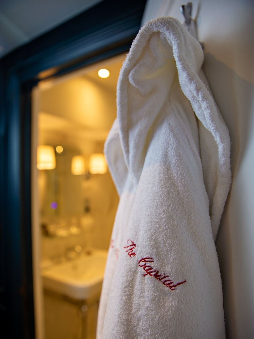 Soft white bathrobe hanging in Hyde Park Suite bathroom at The Capital Hotel, Apartments and Townhouse