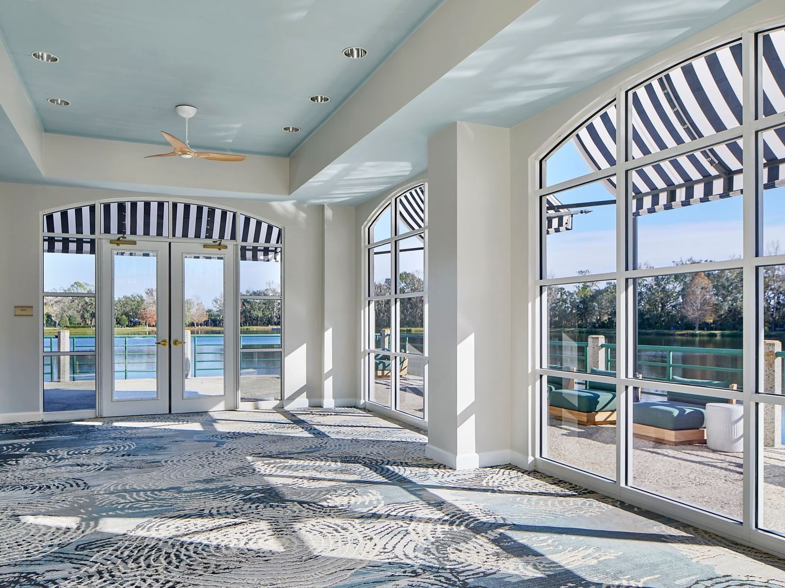 Lake Rianhard at the Inn at Celebration with arched windows, blue-striped awnings, and a view of the water