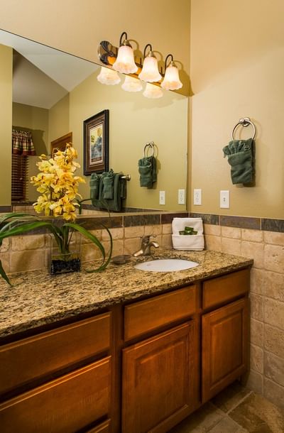 A well-lit bathroom vanity with a granite countertop, wooden cabinets, and a framed mirror at The Stanley Hotel