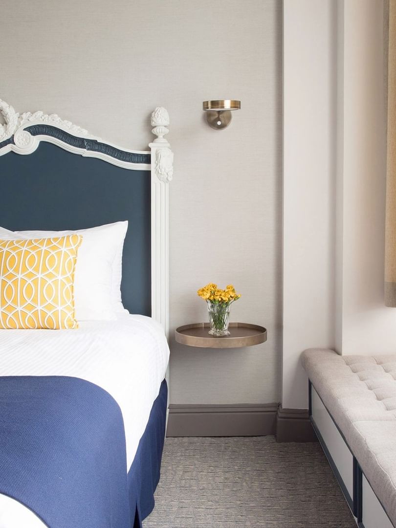Deluxe Queen Room features Bed by a floating metal nightstand under a brass wall sconce at Warwick San Francisco