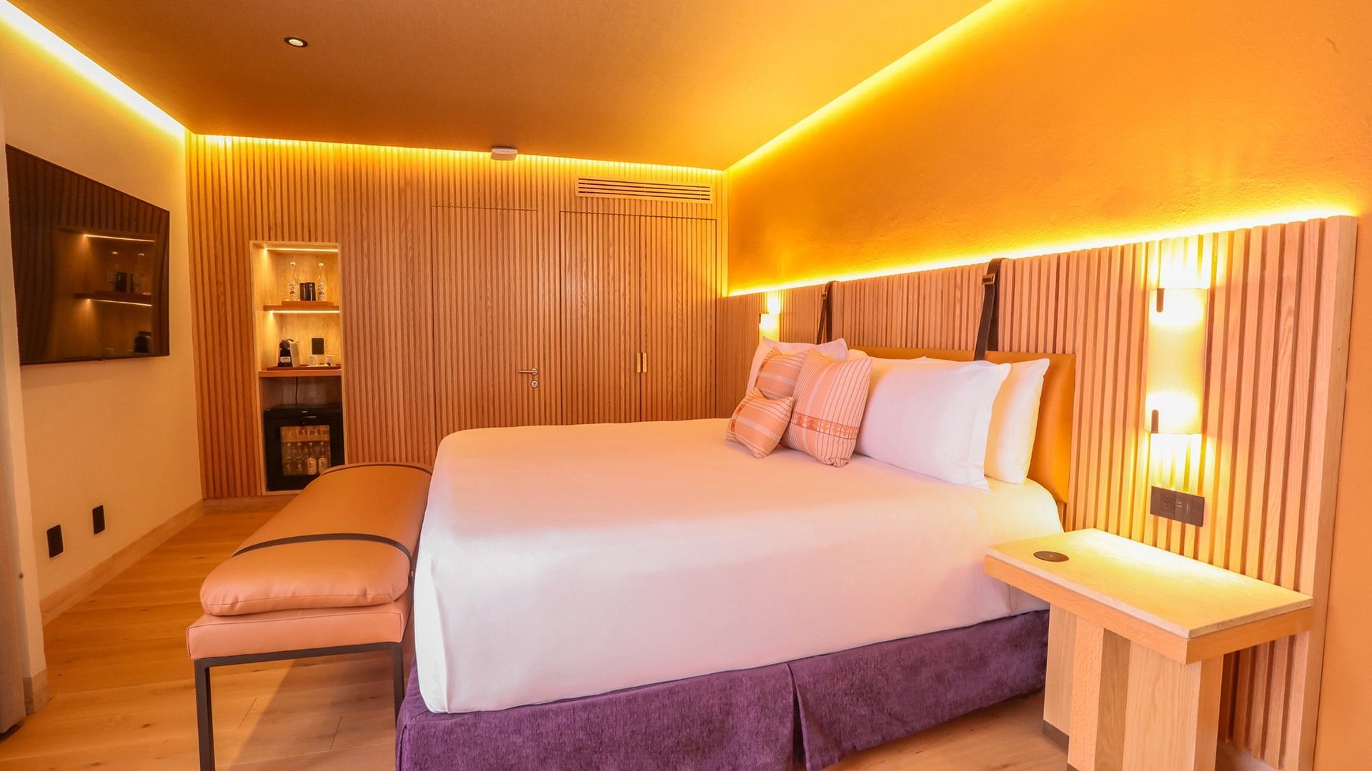 King Superior Junior Suite featuring a purple bed skirt, wood panels, and a mini-fridge at Camino Real Polanco Mexico