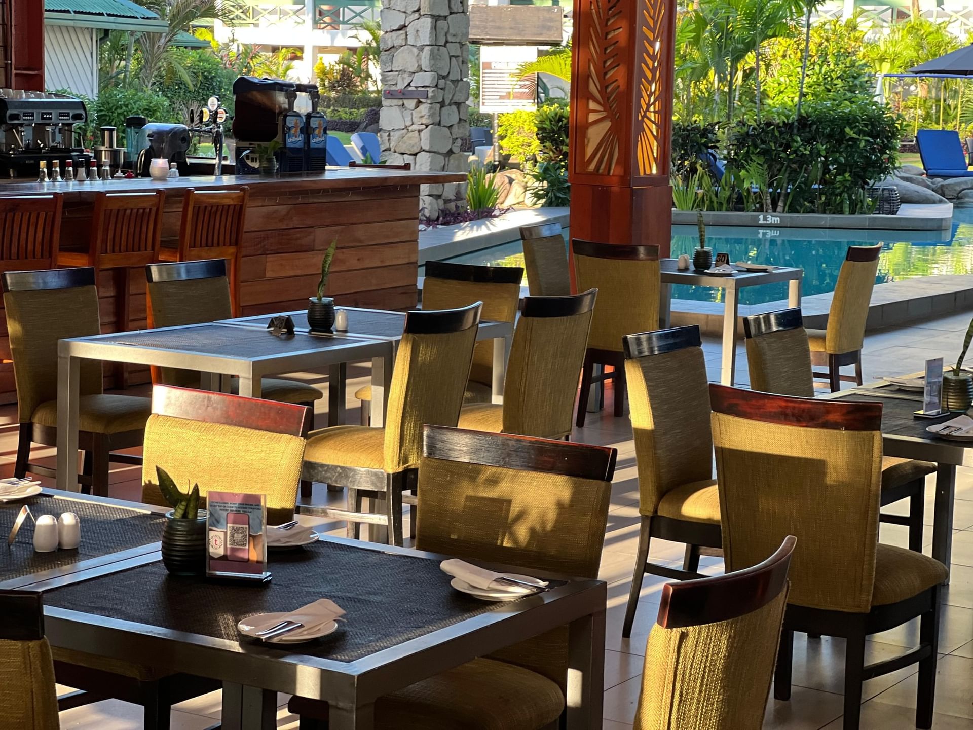 KanaVata Restaurant with set tables and chairs by a wooden bar under a stone pillar at TokaToka Resort Nadi Fiji