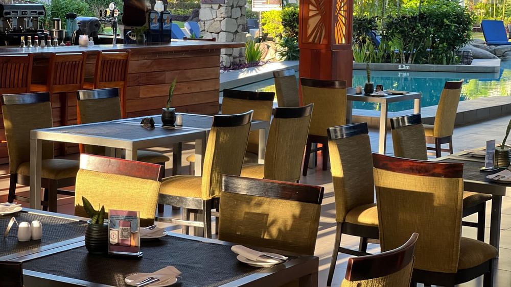 KanaVata Restaurant with set tables and chairs by a wooden bar under a stone pillar at TokaToka Resort Nadi Fiji