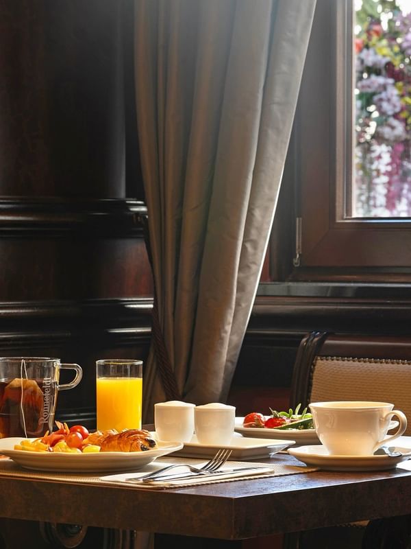 Breakfast table with a cup of tea placed by a plate of pastries near a window at Warwick Grand Place Brussels