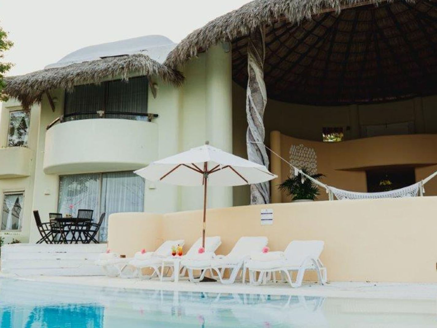 King Presidential Suite featuring a thatched roof villa, private pool, and relaxing white loungers at Quinta Real Huatulco
