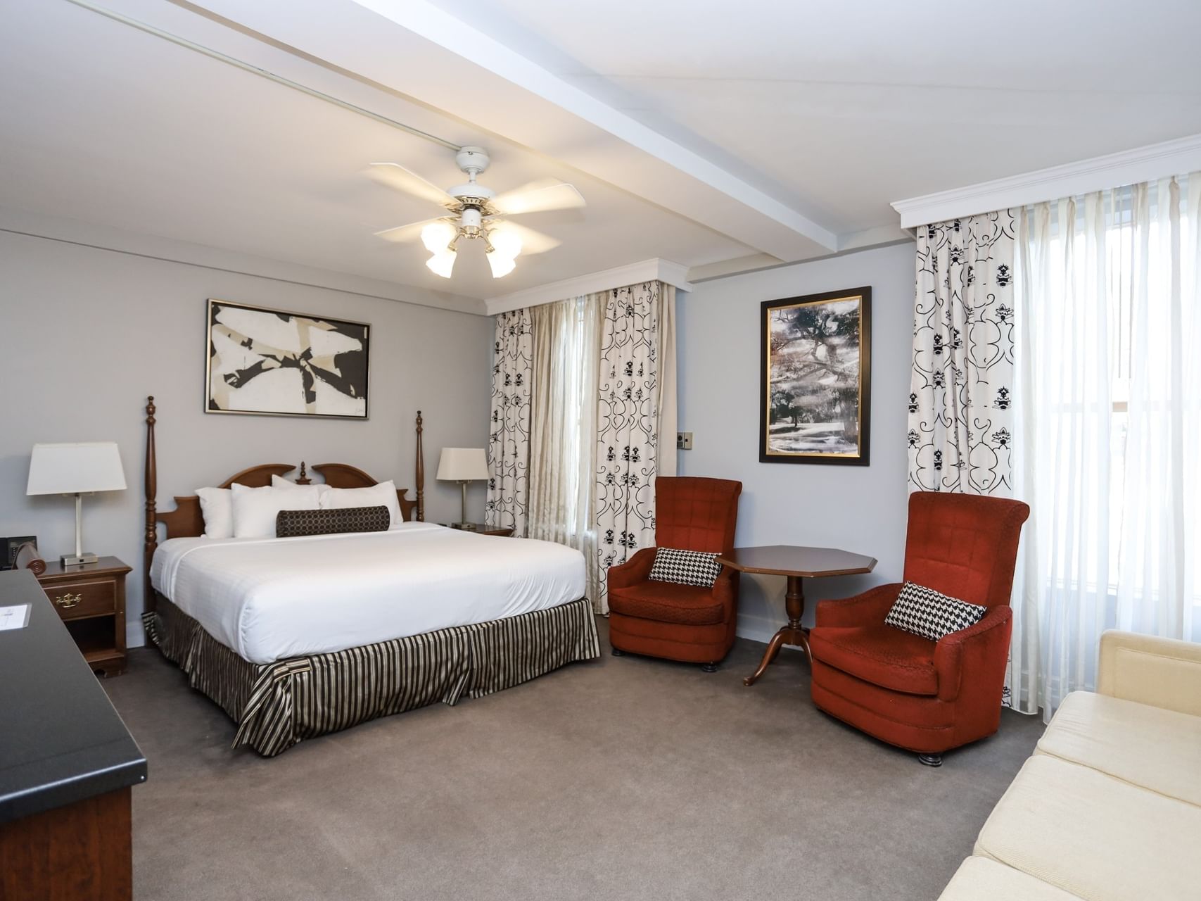 Junior Suite featuring two red lounge chairs and a white sofa by the window at Arlington Resort Hotel & Spa