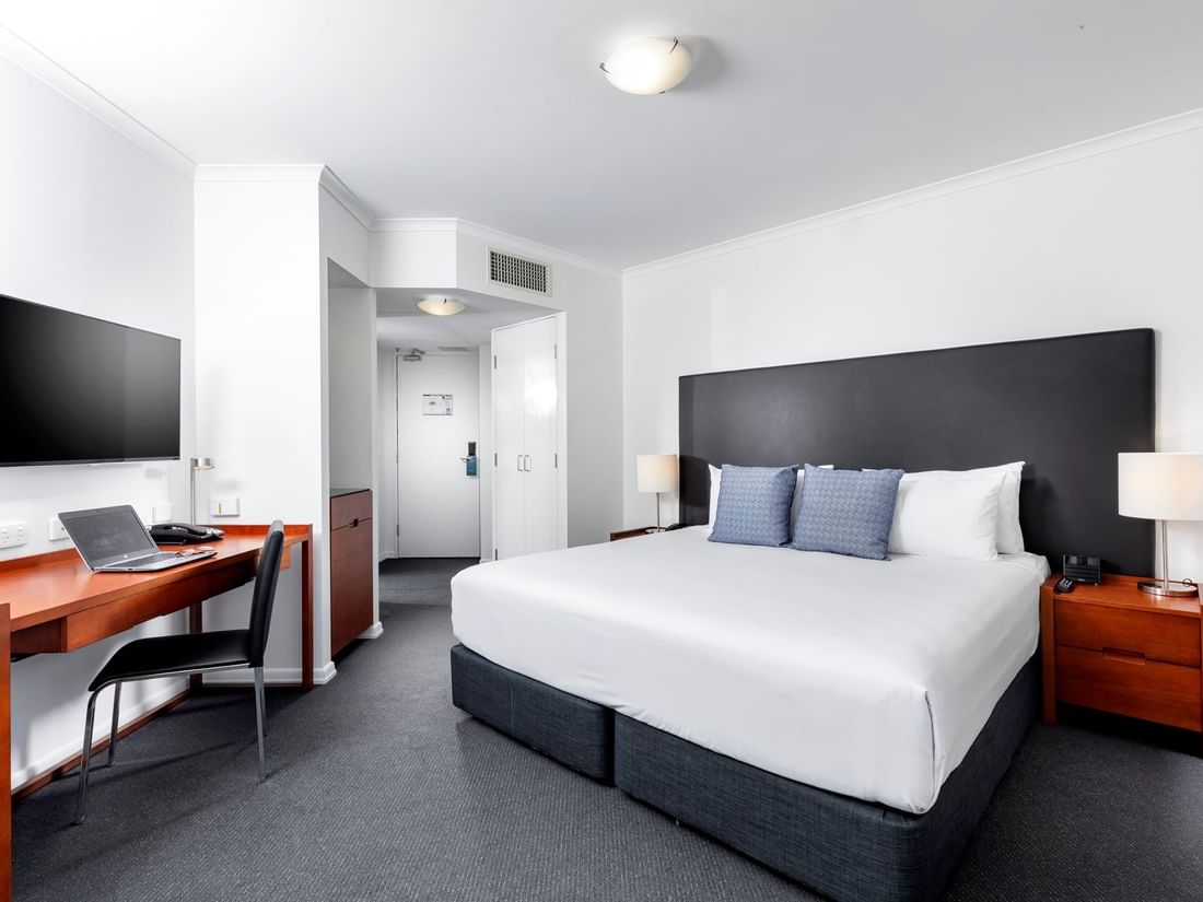 Studio Room featuring a king bed with a dark headboard, a large desk, and a television at The Sebel Brisbane