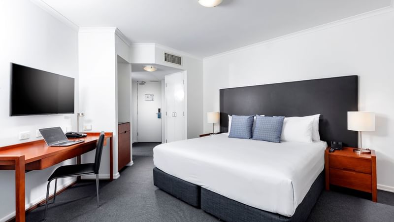 Studio Room featuring a king bed with a dark headboard, a large desk, and a television at The Sebel Brisbane
