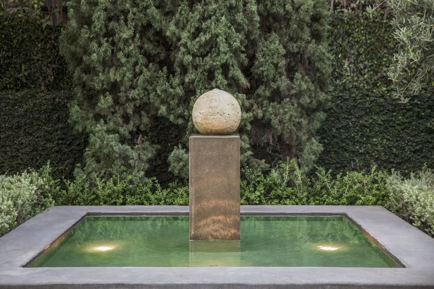Close-up on a stone bollard in a pond at Luxe Sunset Boulevard Hotel
