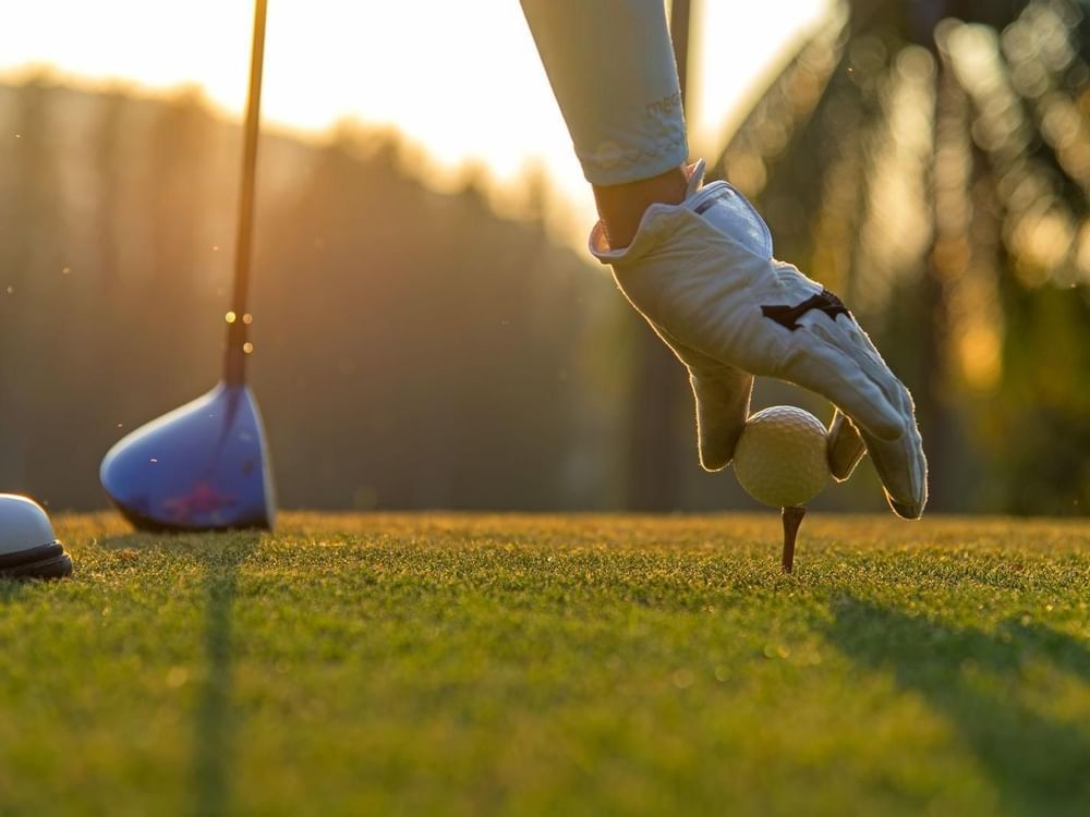 A player placing a golf ball on a tee at Live Aqua Resorts