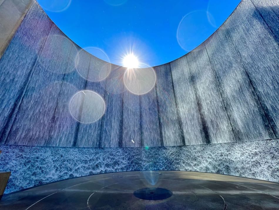 Sunlight streams through the circular waterfall at Gerald D. Hines Waterwall Park near Granduca Houston