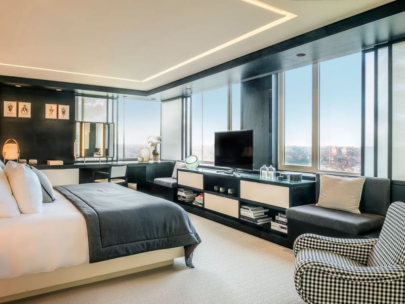 The Suite bedroom with large windows, city view, king bed, and a black-and-white color scheme at The Hotel Brussels