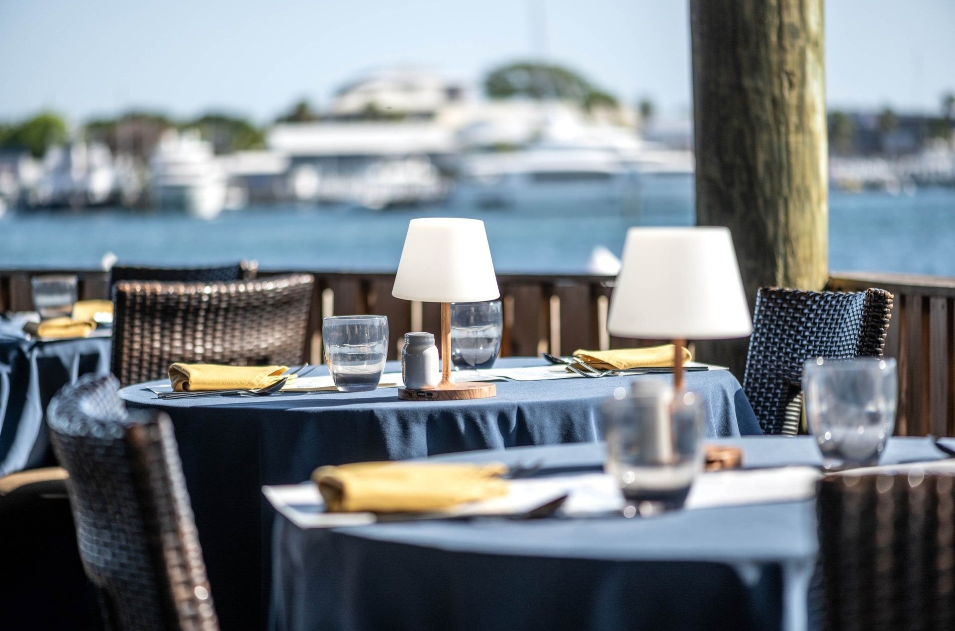 Small white lamps by silverware on blue tables surrounding a fence in Edgewater Grill at Warwick Paradise Island Bahamas