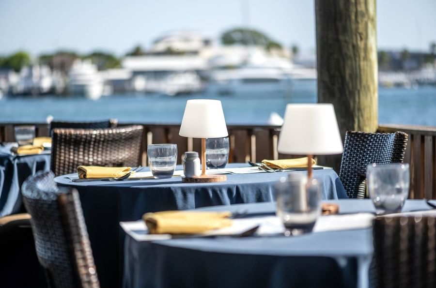 Small white lamps by silverware on blue tables surrounding a fence in Edgewater Grill at Warwick Paradise Island Bahamas