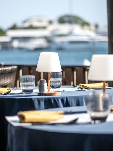 Small white lamps by silverware on blue tables surrounding a fence in Edgewater Grill at Warwick Paradise Island Bahamas