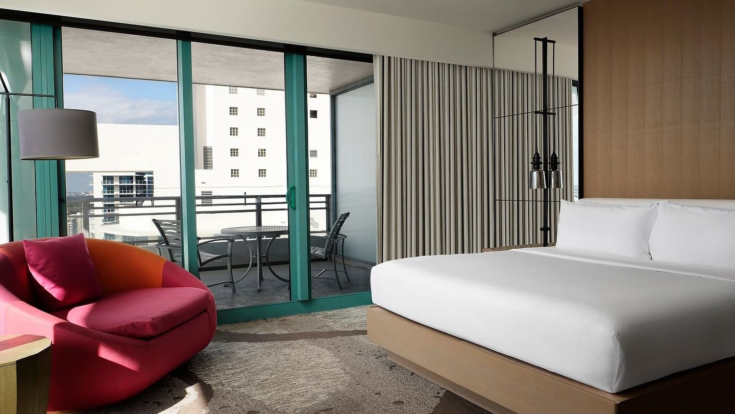 Sun-lit resort guest room with modern furnishings, contemporary design, and private balcony.