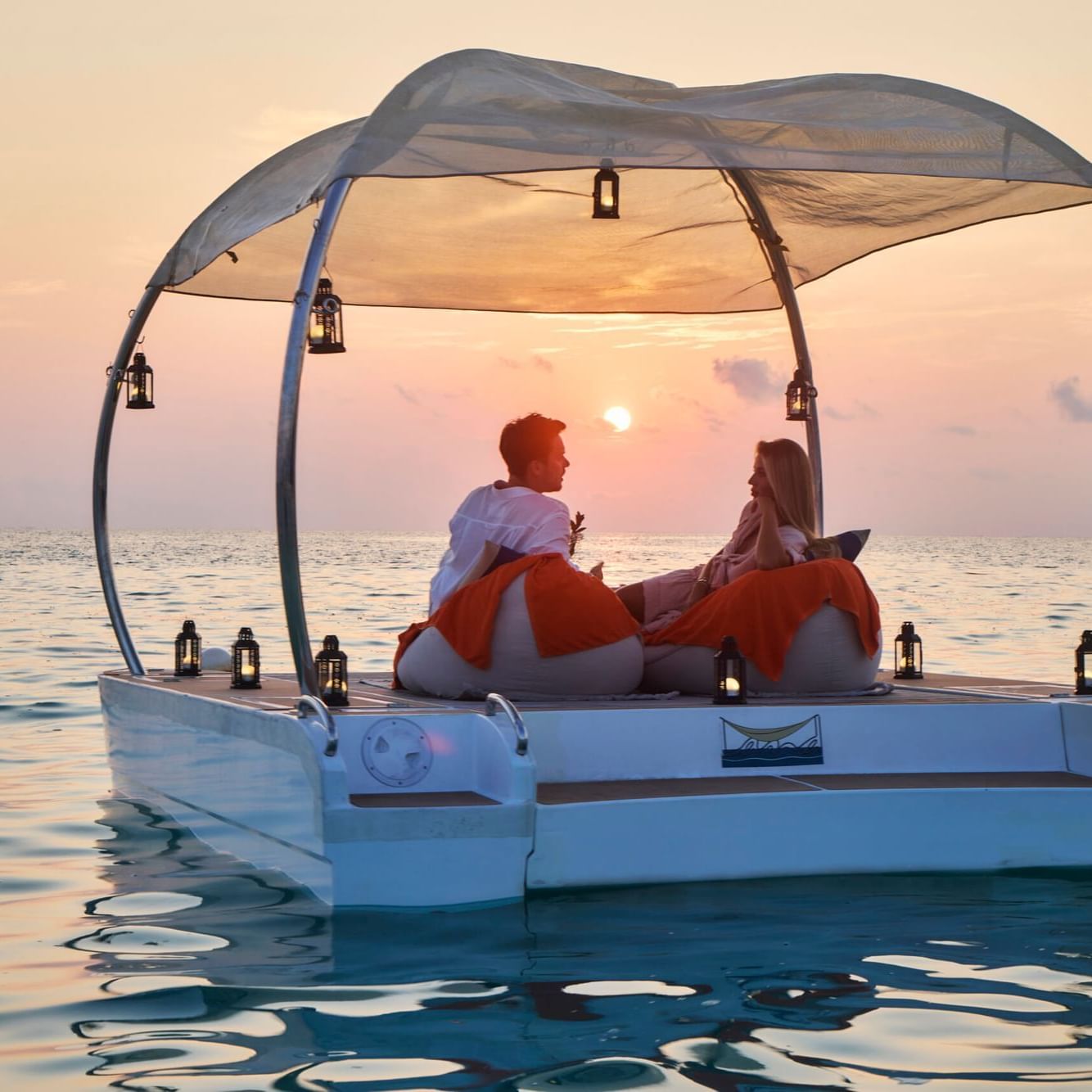 Couple on a boat enjoying sunset over the ocean near Grand Park Kodhipparu, Maldives