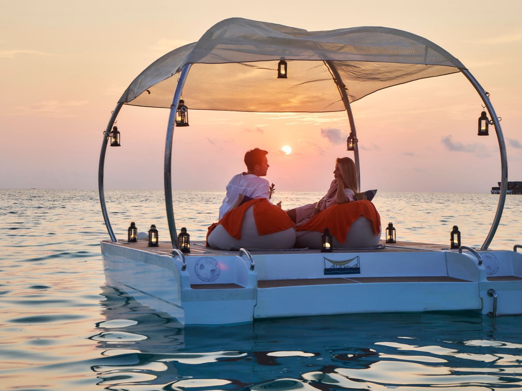 Couple on a boat enjoying sunset over the ocean near Grand Park Kodhipparu, Maldives