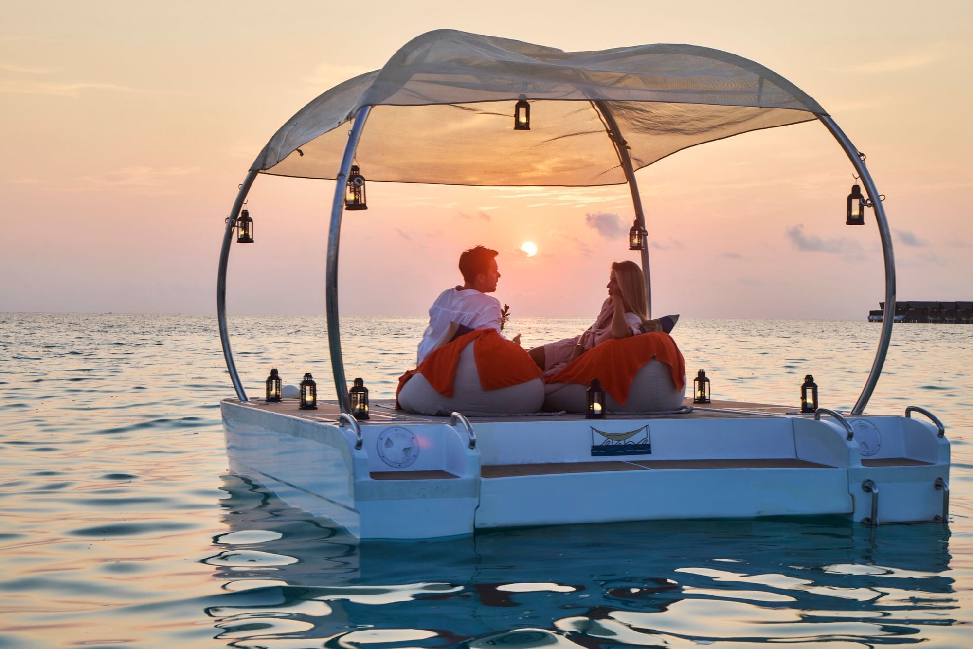 Couple on a boat enjoying sunset over the ocean near Grand Park Kodhipparu, Maldives