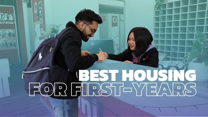 Man with backpack shakes hands with woman at a desk, with