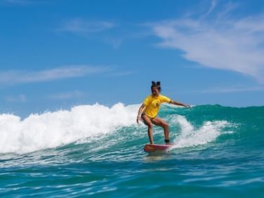 Young surfer girl riding a wave in the beautiful blue ocean at the Maui Coast Hotel