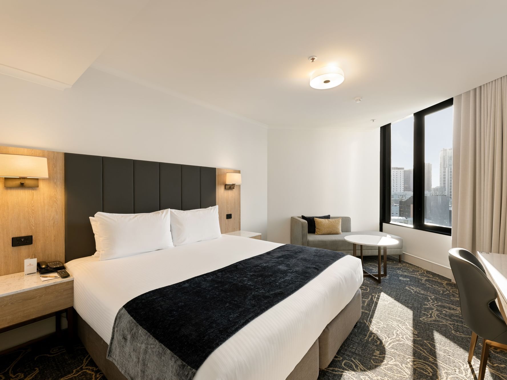 Bed with side lamp and work area in Deluxe King Room at Hotel Grand Chancellor Brisbane