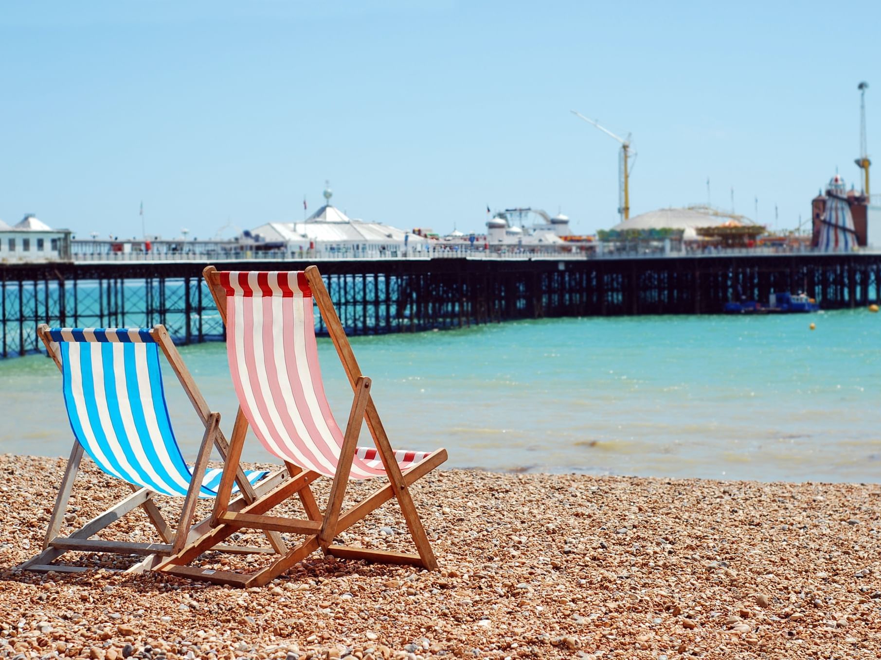 Two beach chairs at the coast of the beach facing the Brighton Palace Pier