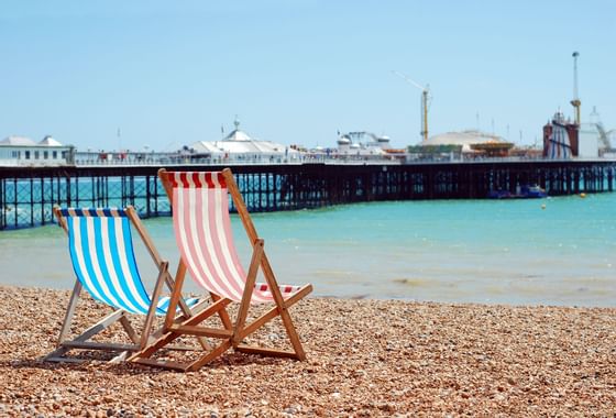 Two beach chairs at the coast of the beach facing the Brighton P