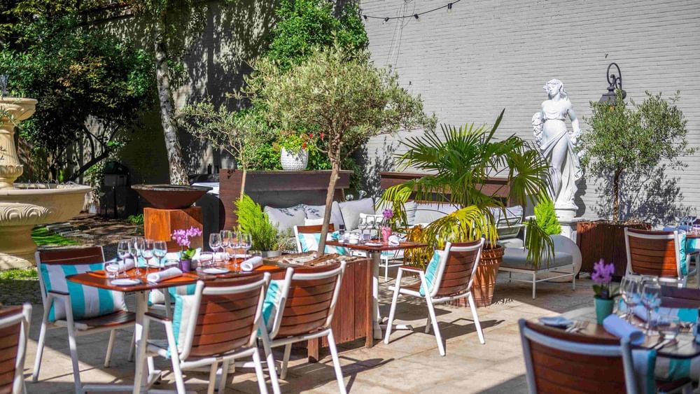 Al fresco dining on the sunlit garden terrace with white statues at Hotel Barsey by Warwick