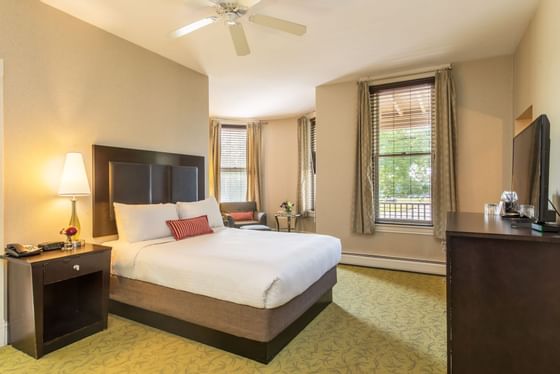 Bedroom with a TV, lamp & sitting area at The Centennial Hotel