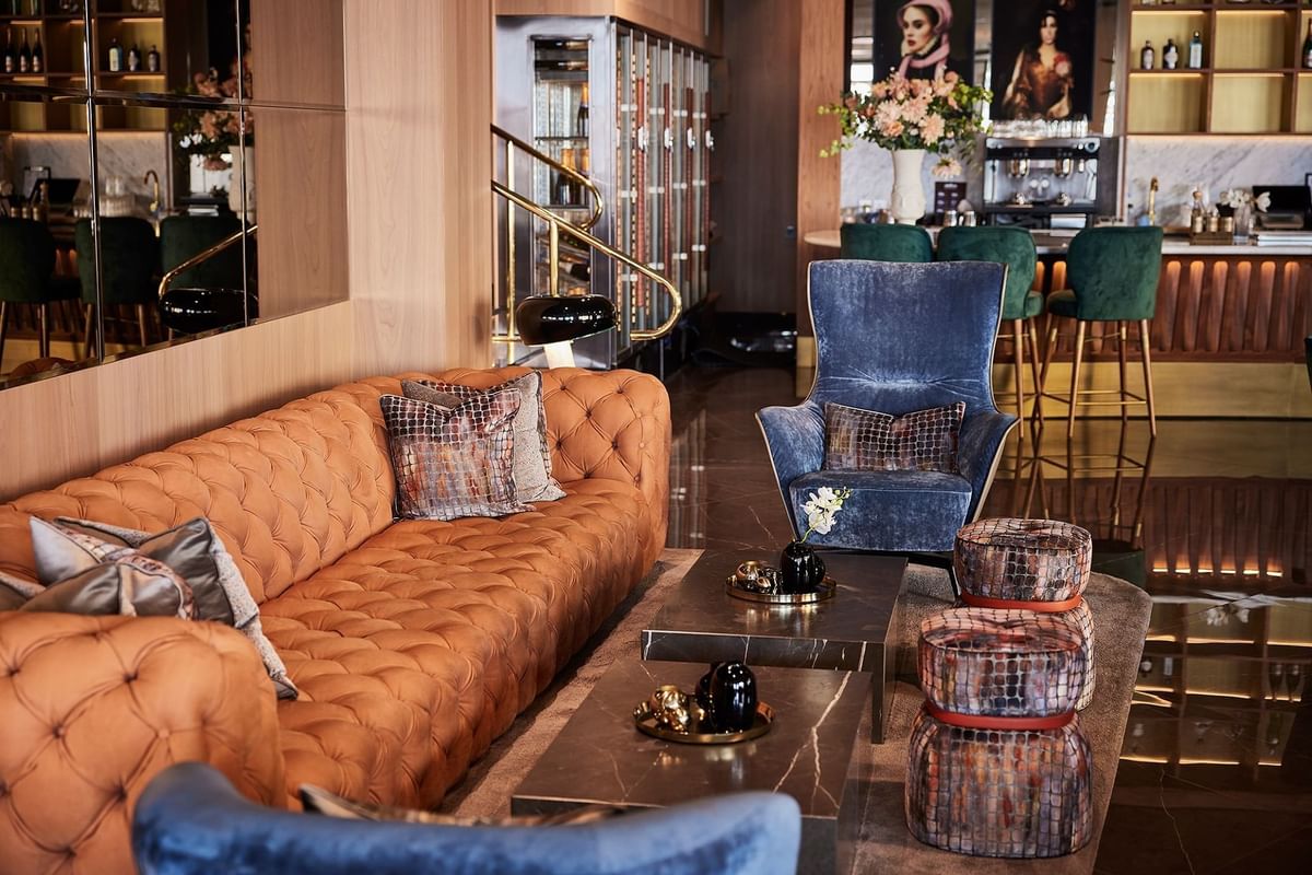 Elegant lounge med orange soffa, blå fåtölj, marmorbord och väggspegel i lyxig inredning.