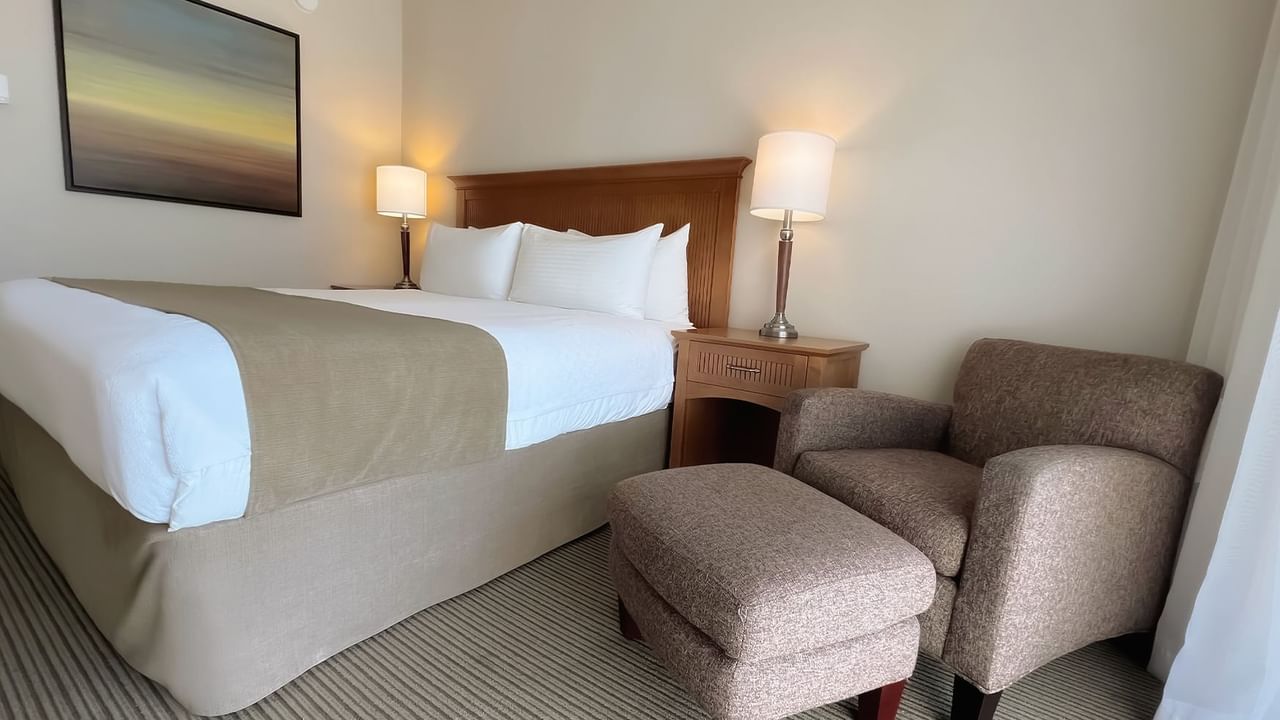 Guest room with king bed, lamps and chair