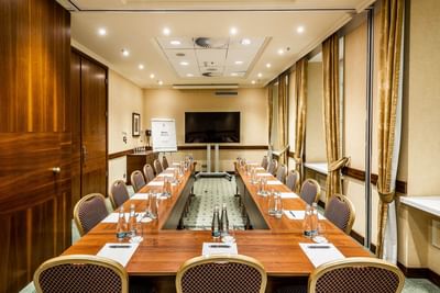 Conference room with a U-shaped table, chairs, and presentation equipment at Polonia Palace Hotel