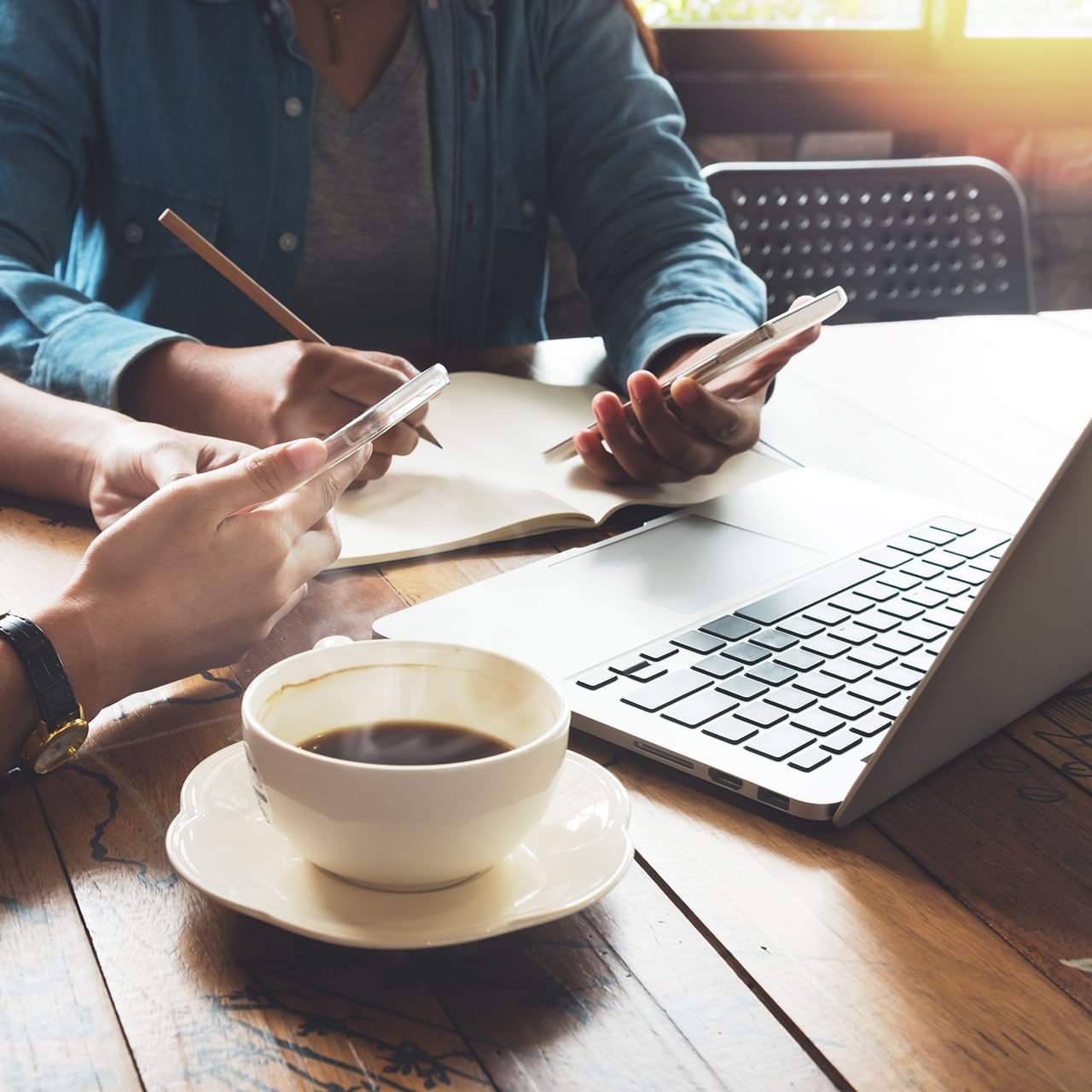 Two people working in a table with a laptop, notebook, and a cup of coffee at Hotel 43