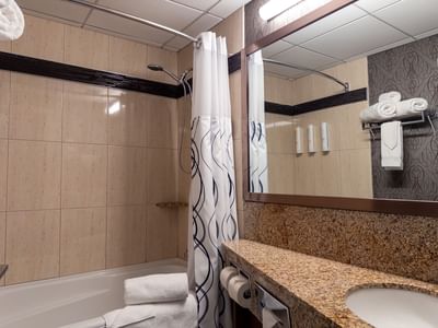 Clean bathroom with shower, sink, and towels at Carriage House Hotel & Conference Centre