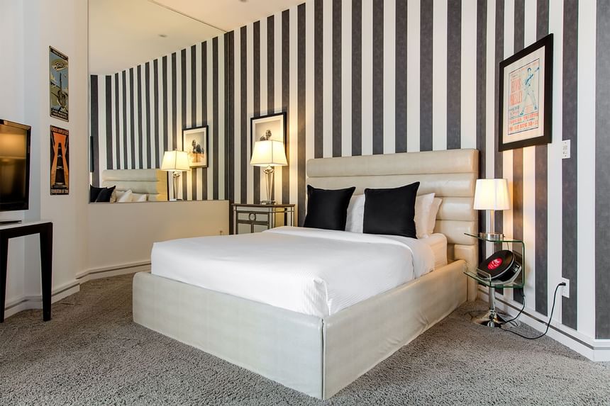 King-size bed, lamps & carpeted floor in Queen Premier Rock & Roll  at Retro Suites Hotel