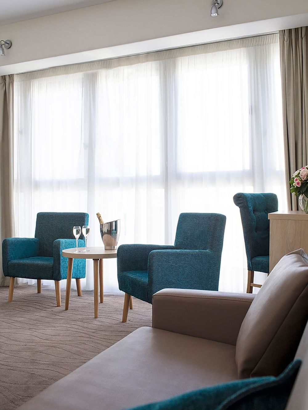 Cozy seating area with teal chairs and an ice bucket with sparkling beverage in the Suites at Splendid Hotel & Spa Nice