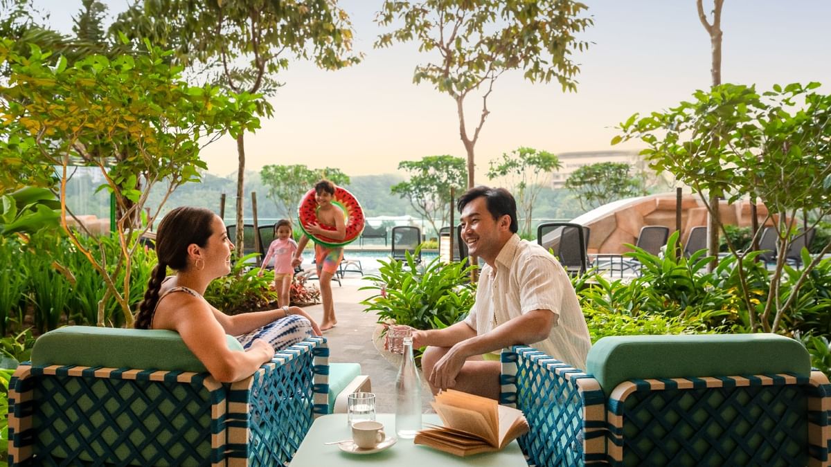 Family relaxing by the pool as a child plays with a watermelon float in Waterventure Terrace at Sunway Resort