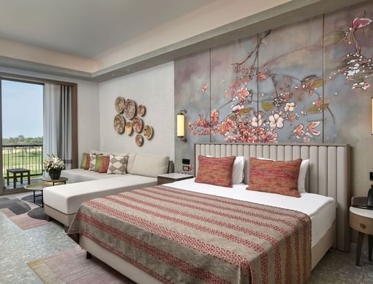 Seating area by the bed in Superior Room Golf View with floral wall art at Cullinan Belek
