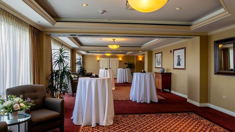 Cocktail tables with white cloths by an armchair under dome in Millennium at Warwick Denver
