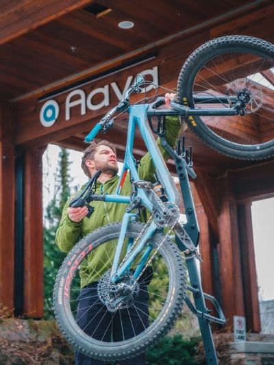 A man holding his mountain bike at Aava Whistler Hotel