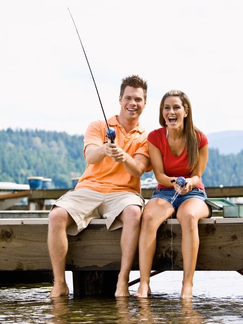 Couple fishing by the lake with smiles on their faces near Cove Pocono Resorts