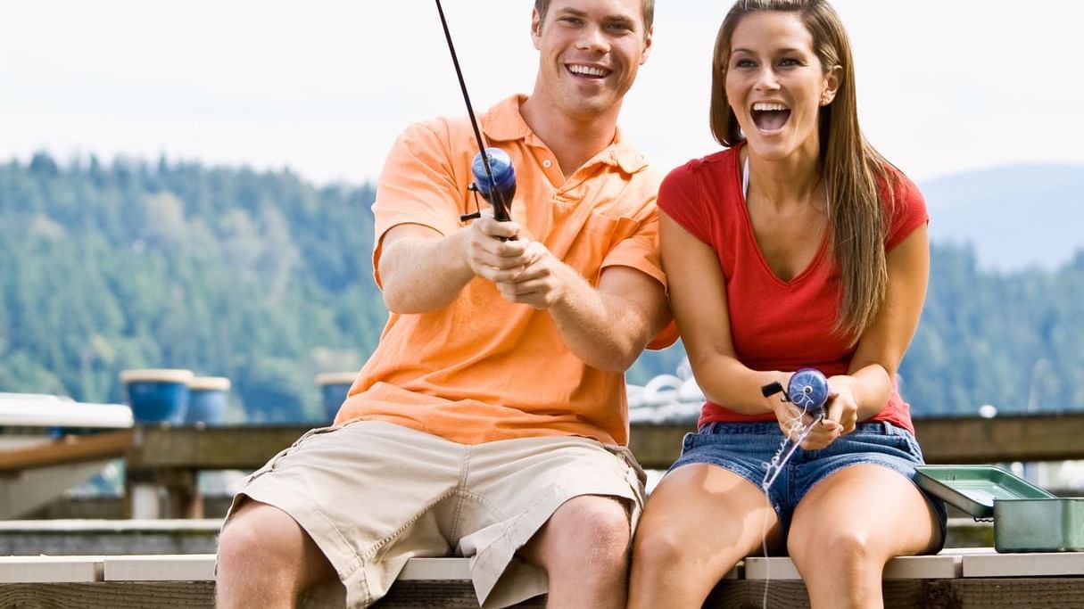Couple fishing by the lake with smiles on their faces near Cove Pocono Resorts