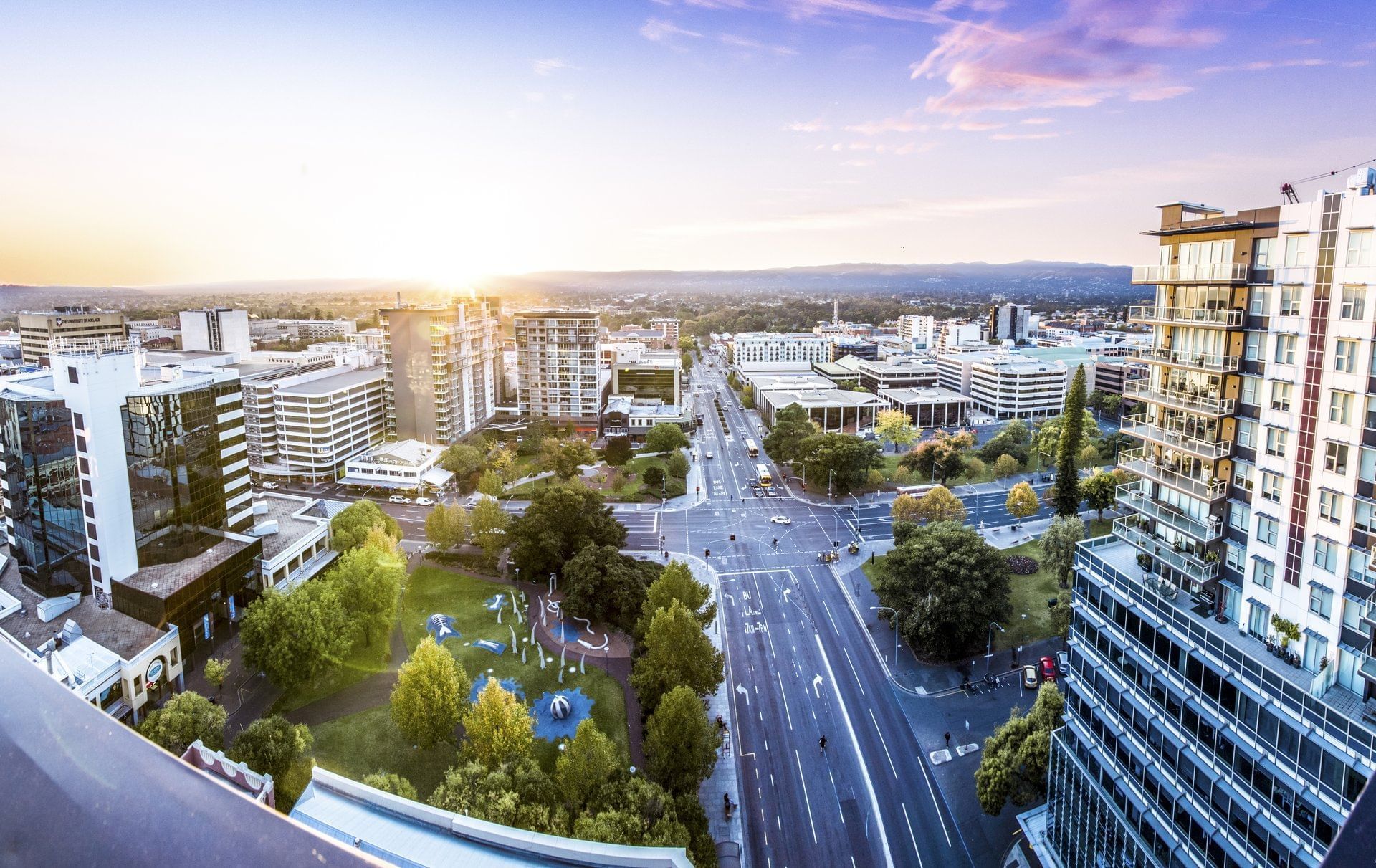Panoramic view of the cityscape with urban buildings, busy roads, and a green park near Ibis Adelaide