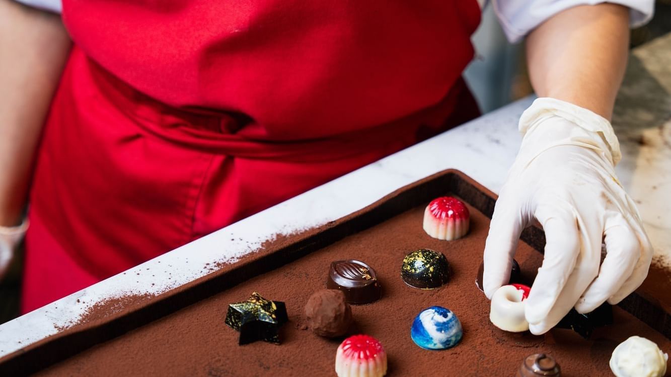 Chef crafting artisan chocolates at Paramount Hotel Dubai, featuring a selection of hand-decorated sweets