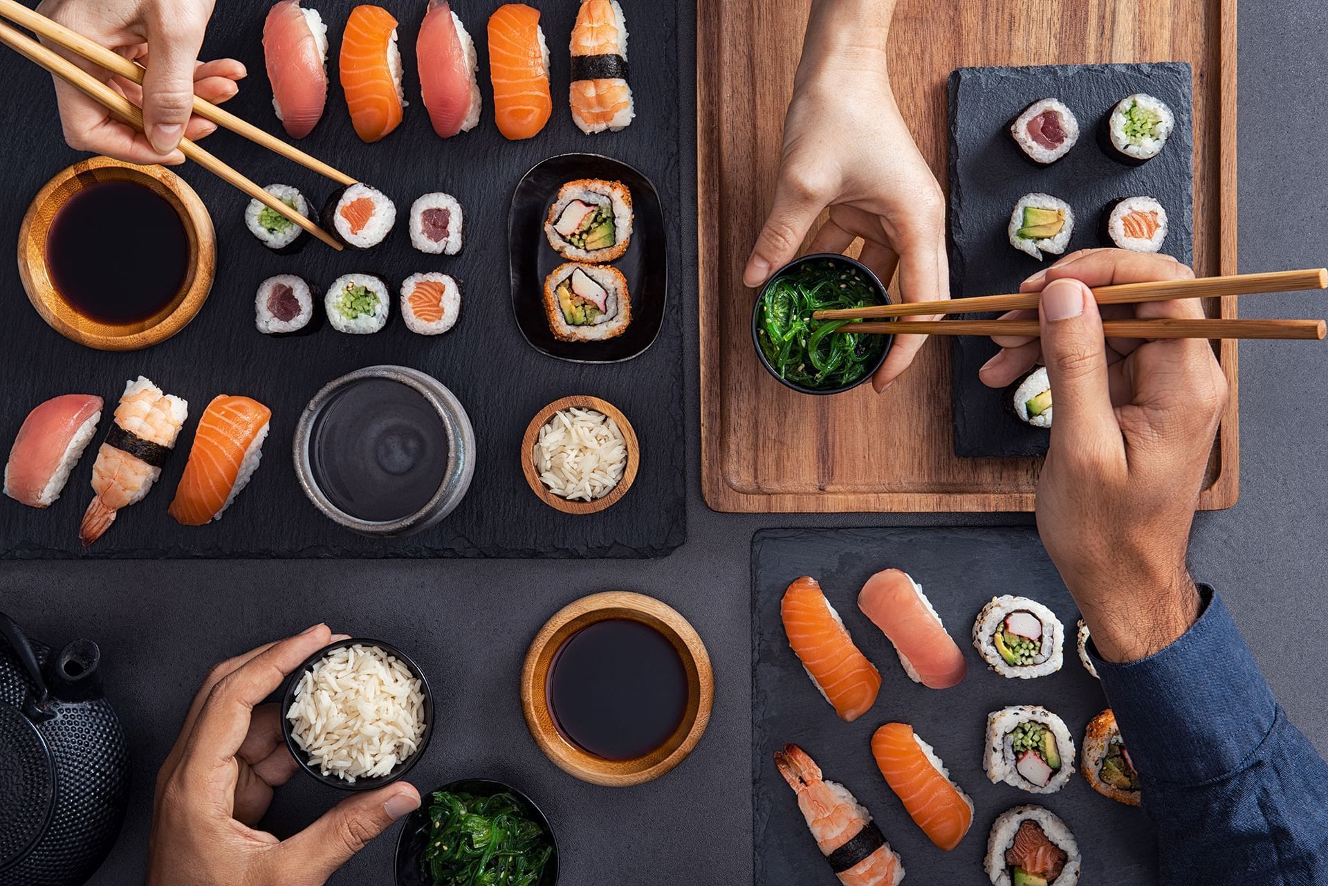 Two people sharing sushi with chopsticks in Gosuke at Henn Na Hotel New York, a hotel restaurant Midtown Manhattan