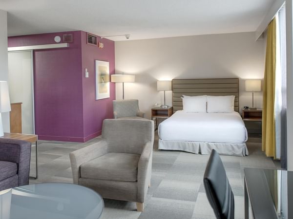 Spacious accessible queen junior suite with seating area, purple accent wall, and modern furnishings at Coast Prince George Hotel.