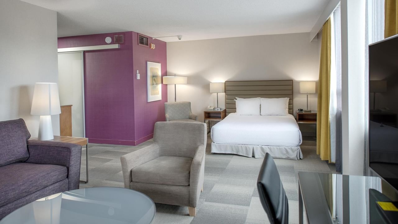 Spacious accessible queen junior suite with seating area, purple accent wall, and modern furnishings at Coast Prince George Hotel.