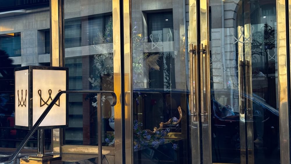 Glass doors by a square lamp under a blue sky reflecting the street view at Warwick Paris Champs Elysées