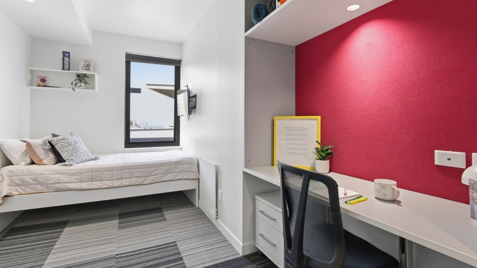 Modern room with bed, desk, chair, and window at UniLodge Auckland City.